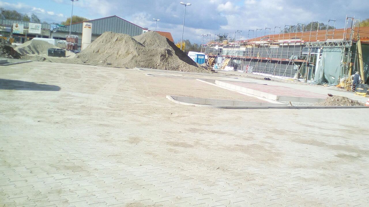 Großflächig gepflasterter Parkplatz eines Einkaufszentrums während der Bauphase