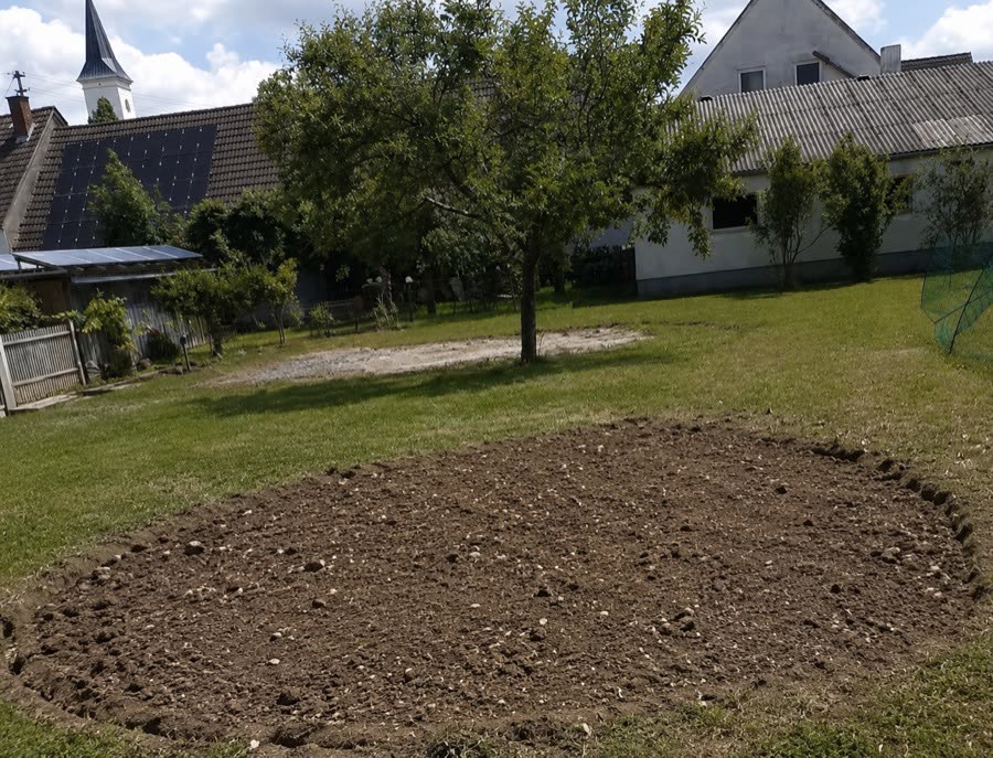 Dieselbe Gartenfläche vor dem Pflastern: vorbereitete runde Erdfläche